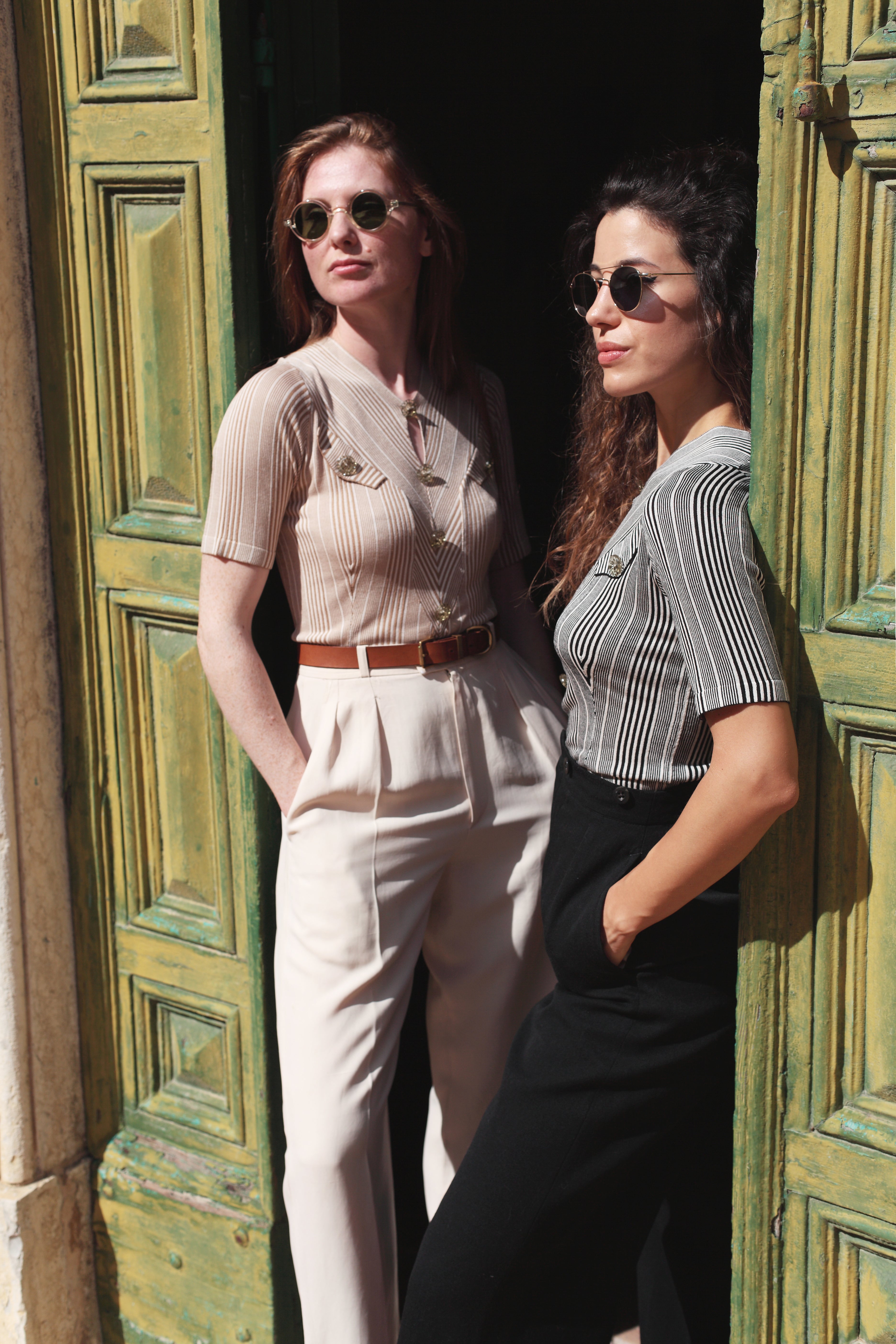 Combelle Alix Top lifestyle shot, two models lounging in green doorway wearing fawn and black colourways