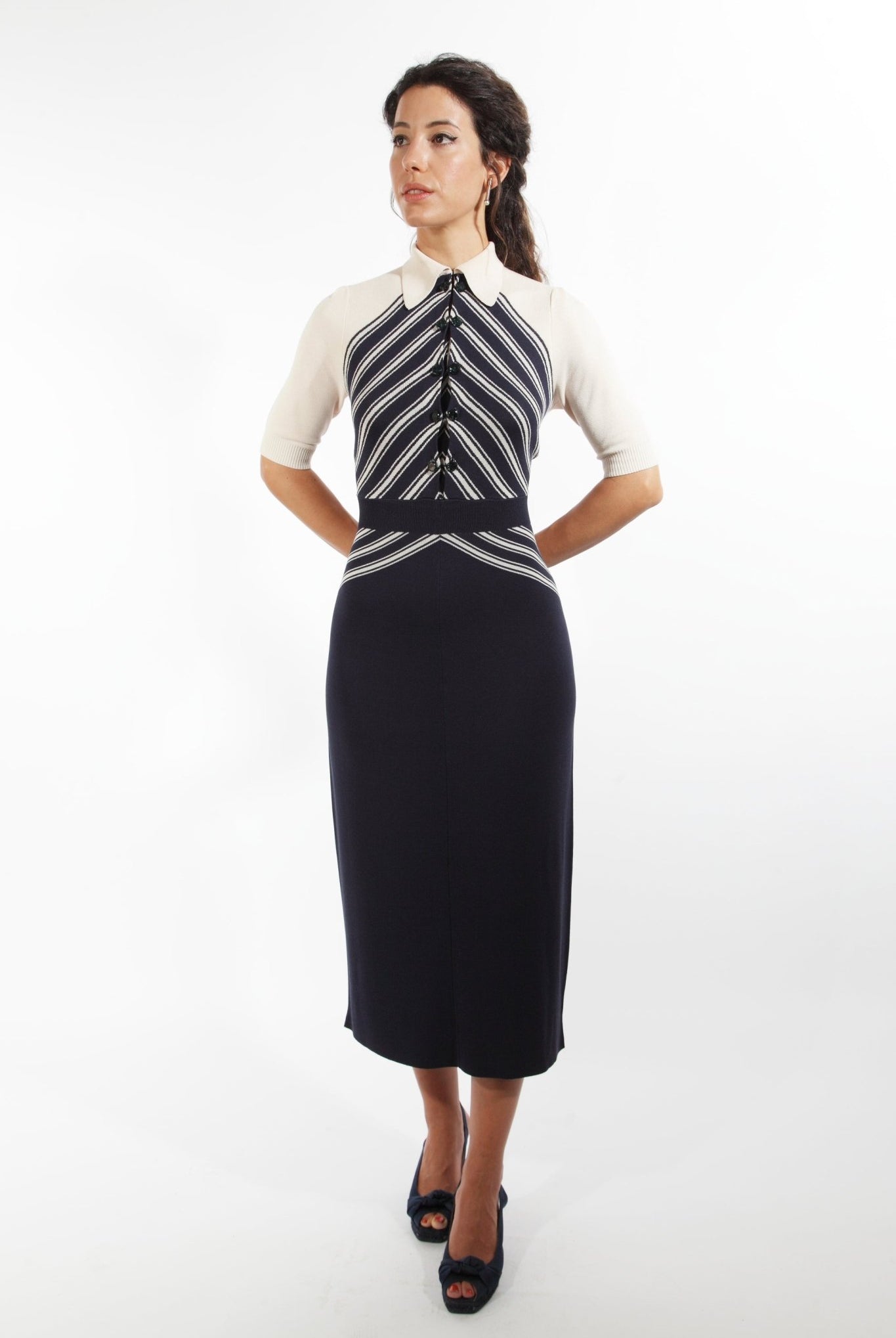 Combelle Colbert Dress full-length front view with hands behind back, diagonal stripe knit bodice with dark pencil skirt