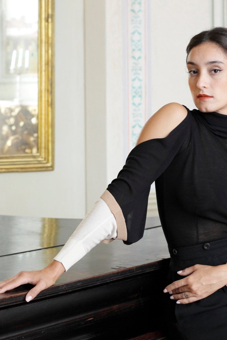 Combelle Elsa Top in black, side view seated in an ornate interior setting showing the sleeve drape and silhouette