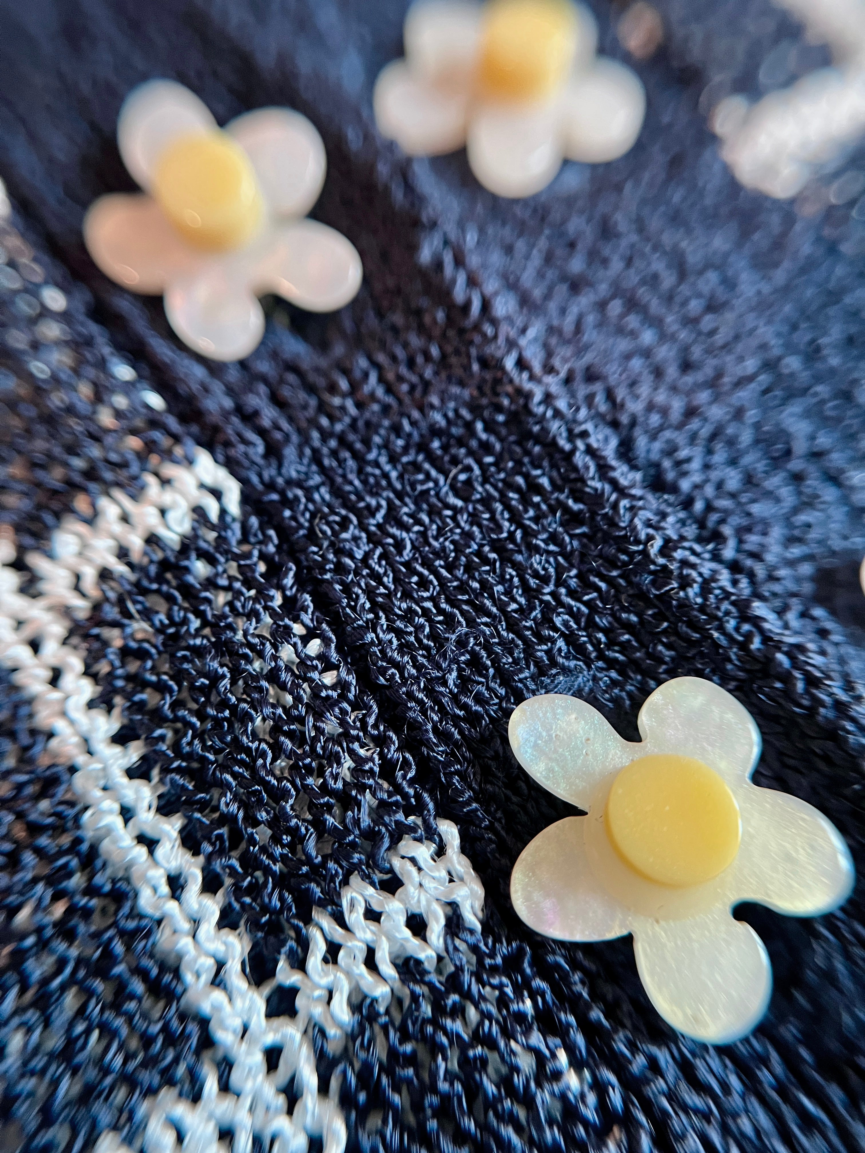 Combelle Madison Top navy daisy chain cufflink button detail — removable daywear buttons in pearlescent white with yellow centre, shown against the two-tone check knit