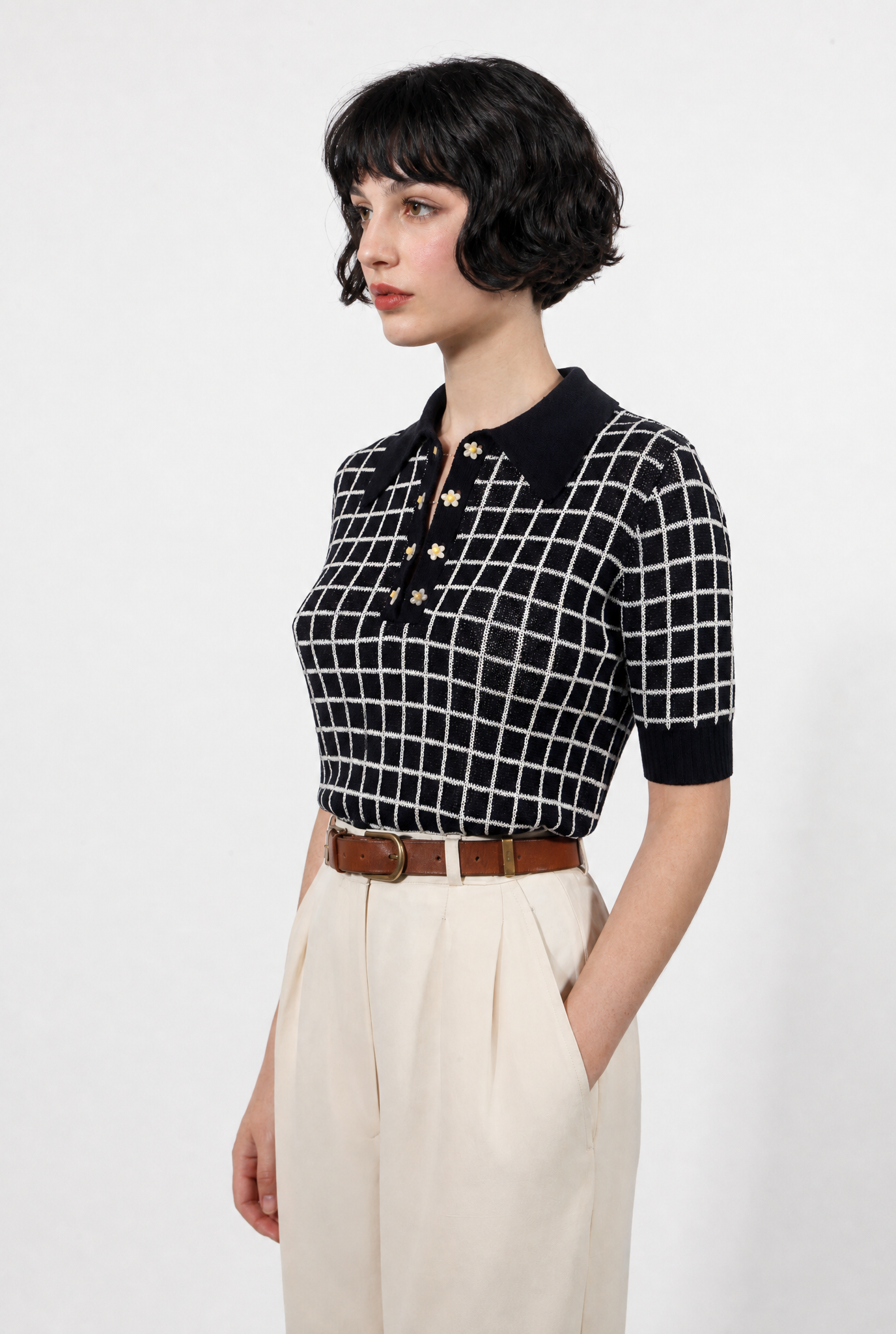 Combelle Madison Top in navy, three-quarter front view showing the two-tone check pattern and daisy chain cufflink buttons, styled with cream wide-leg trousers and a tan belt