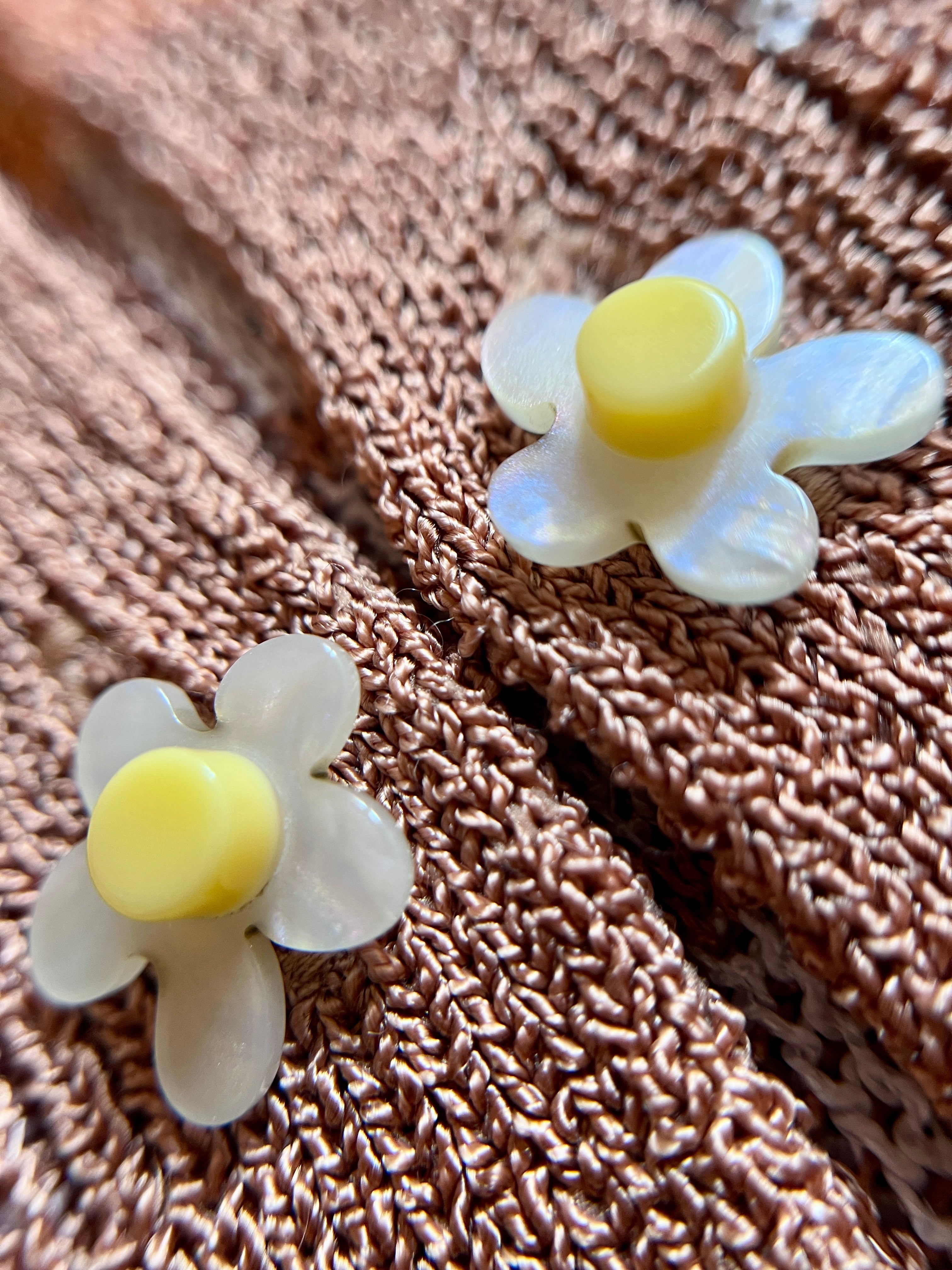 Combelle Madison Top tobacco daisy chain cufflink button detail — removable daywear buttons in pearlescent white with yellow centre, shown against the warm two-tone check knit