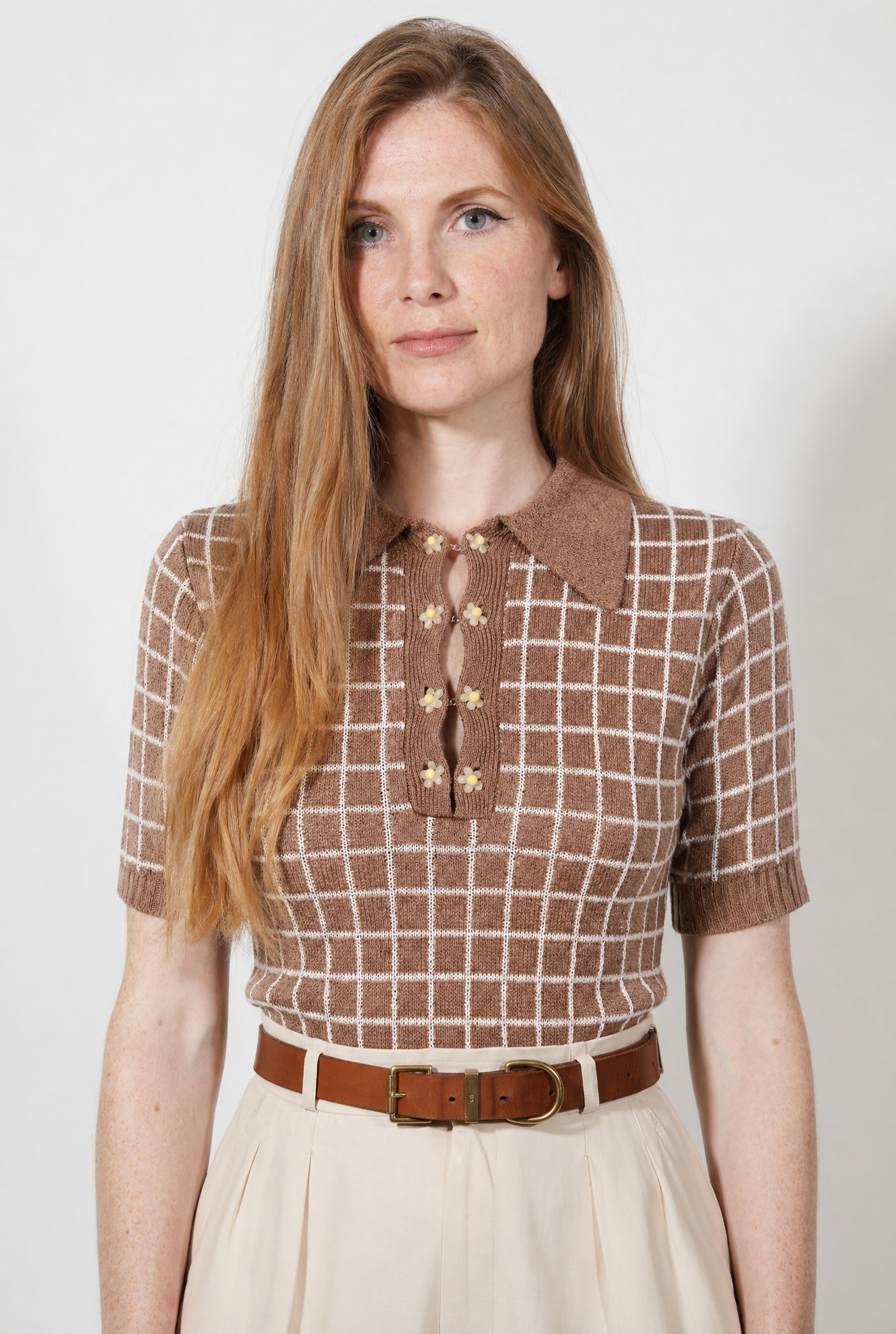 Combelle Madison Top in tobacco, front view showing the warm two-tone check pattern and daisy chain cufflink buttons, styled with cream wide-leg trousers and a tan belt
