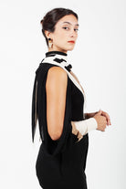 Combelle Elsa Top in black, side view with open shoulder exposed and rabbit ear ties and the Frida foulard pulled behind the collar for evening wear