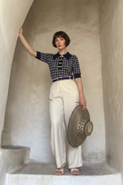 Combelle Madison Top in navy styled with cream trousers, full length lifestyle shot in an outdoor setting evoking 1930s Italian Riviera elegance