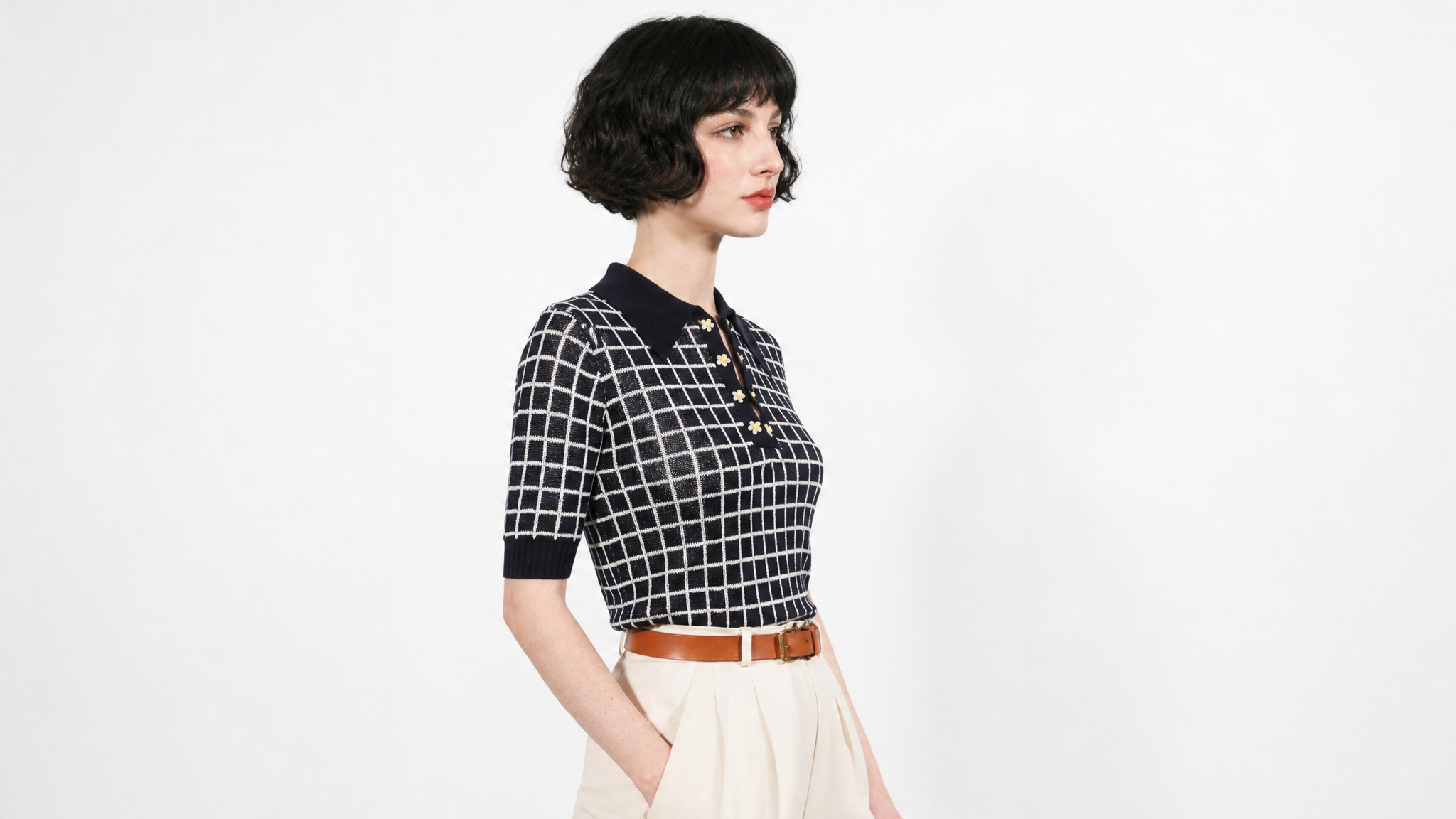 Combelle Madison Top in navy, three-quarter front view showing the two-tone check pattern and daisy chain cufflink buttons, styled with cream wide-leg trousers and a tan belt
