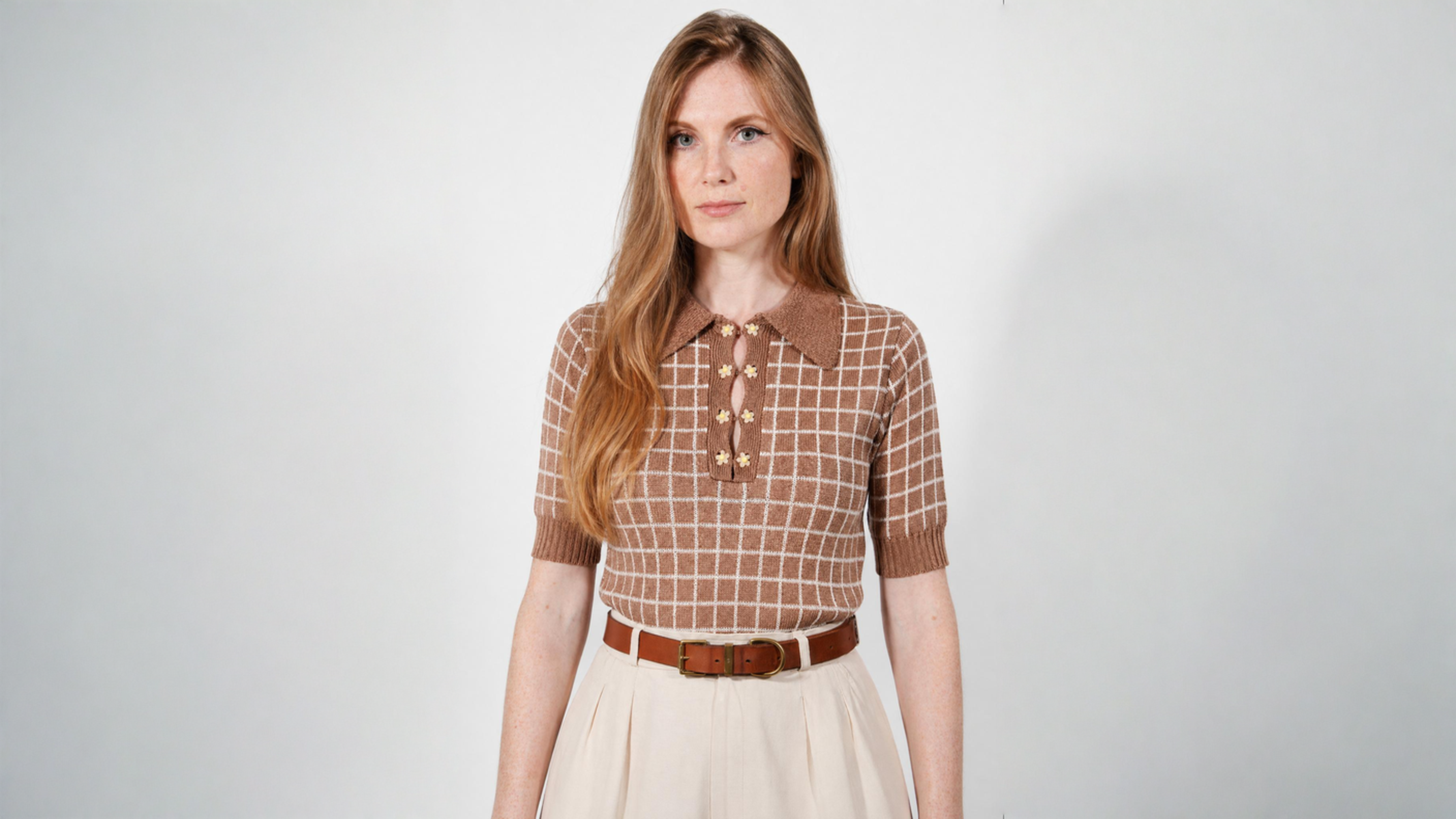 Combelle Madison Top in tobacco, front view showing the warm two-tone check pattern and daisy chain cufflink buttons, styled with cream wide-leg trousers and a tan belt