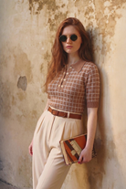Combelle Madison Top in tobacco, three-quarter front lifestyle shot against a warm stone wall showing the relaxed literary authority of the silhouette