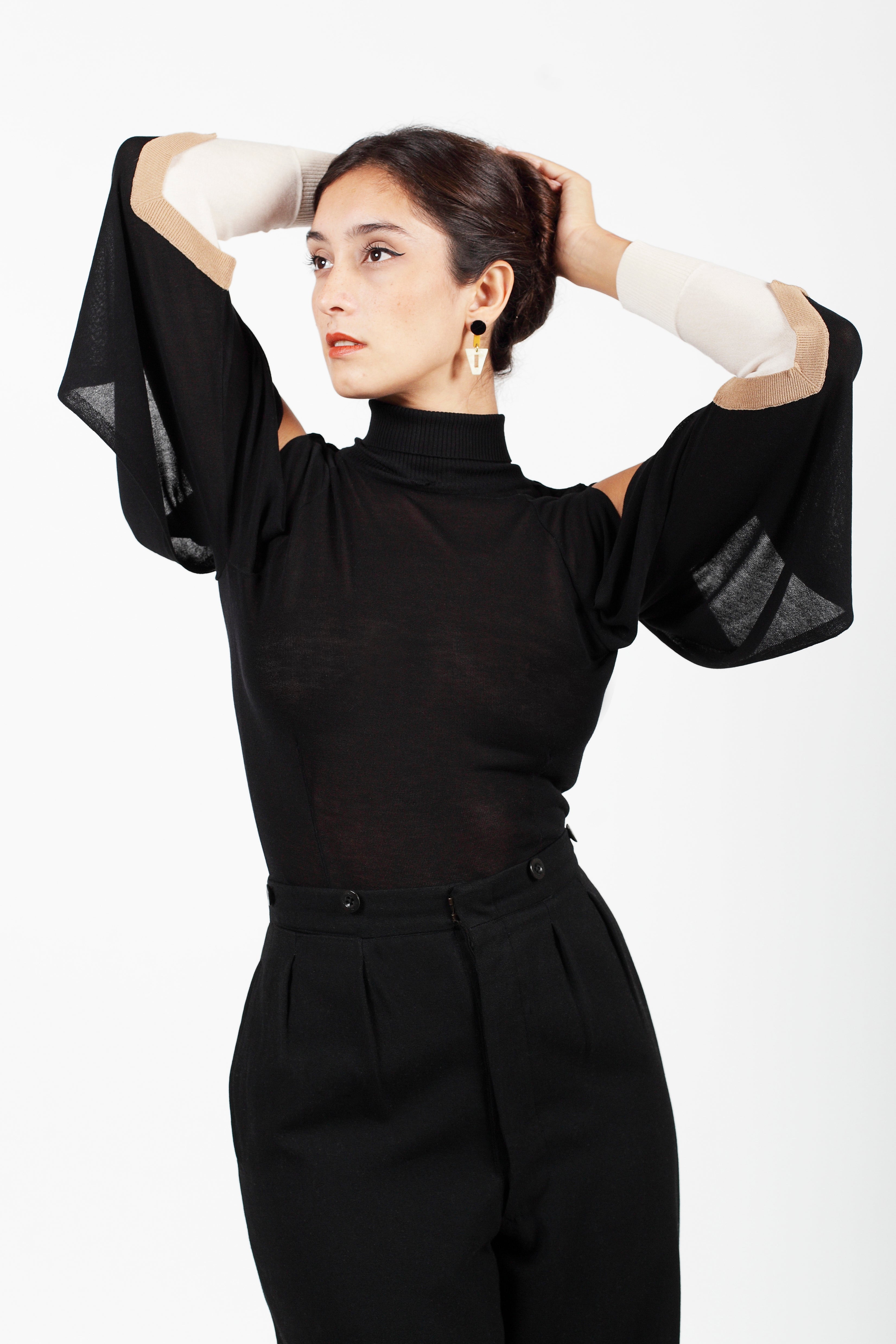 Combelle Elsa Top in black, front view with arms raised showing the dramatic open drape sleeve and high ribbed collar